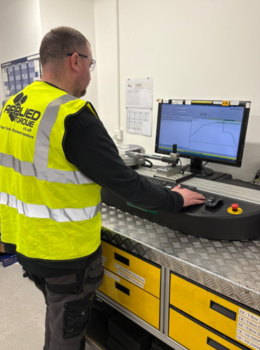 Close-up of a technician calibrating a torque wrench using a calibration machine, with the wrench and precision equipment in focus to highlight the calibration process.
