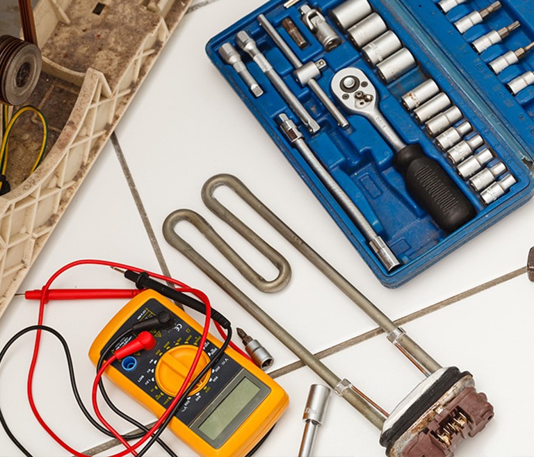 Torque Tool service And Repair Demonstration image from the Applied Torque workshop. Showing a work bench scenario with torque wrench and socket set, multi-meter and heating element all being serviced.