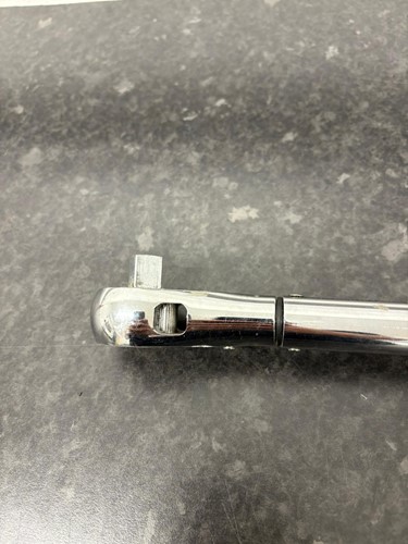 Close-up of a torque wrench with visible damage such as a cracked handle, worn scale, or bent head, focusing on physical signs of wear that indicate the need for calibration.